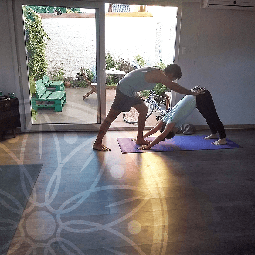 Instructor ayudando a alumna a hacer una posición de yoga
